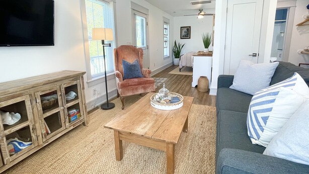 Un salon spacieux avec une table basse en bois, un canapé moelleux, un fauteuil en velours et un téléviseur à écran plat fixé au mur.