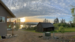 Ländliche Landschaft mit einem Haus, einem Holzschuppen und einer Schotterauffahrt zu einem Steg.