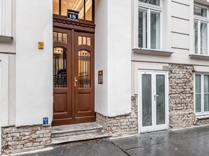 A two-story building with a brown double door and a stone facade.