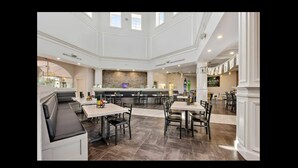 A spacious, well-lit dining area with high ceilings and a central island. - FUNCATION VILLA (Davenport)