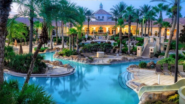 A resort with a large central pool, palm trees, and a building with a tiled roof. - FUNCATION VILLA (Davenport)