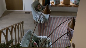 A room with a wooden door, a window seat with cushions, a patterned rug, and a chair with a floral pillow. - Pet Friendly, Near O’Hare, Fenced in, Cheerful Frida & Diego Home, up to 6 ppl (Wood Dale)