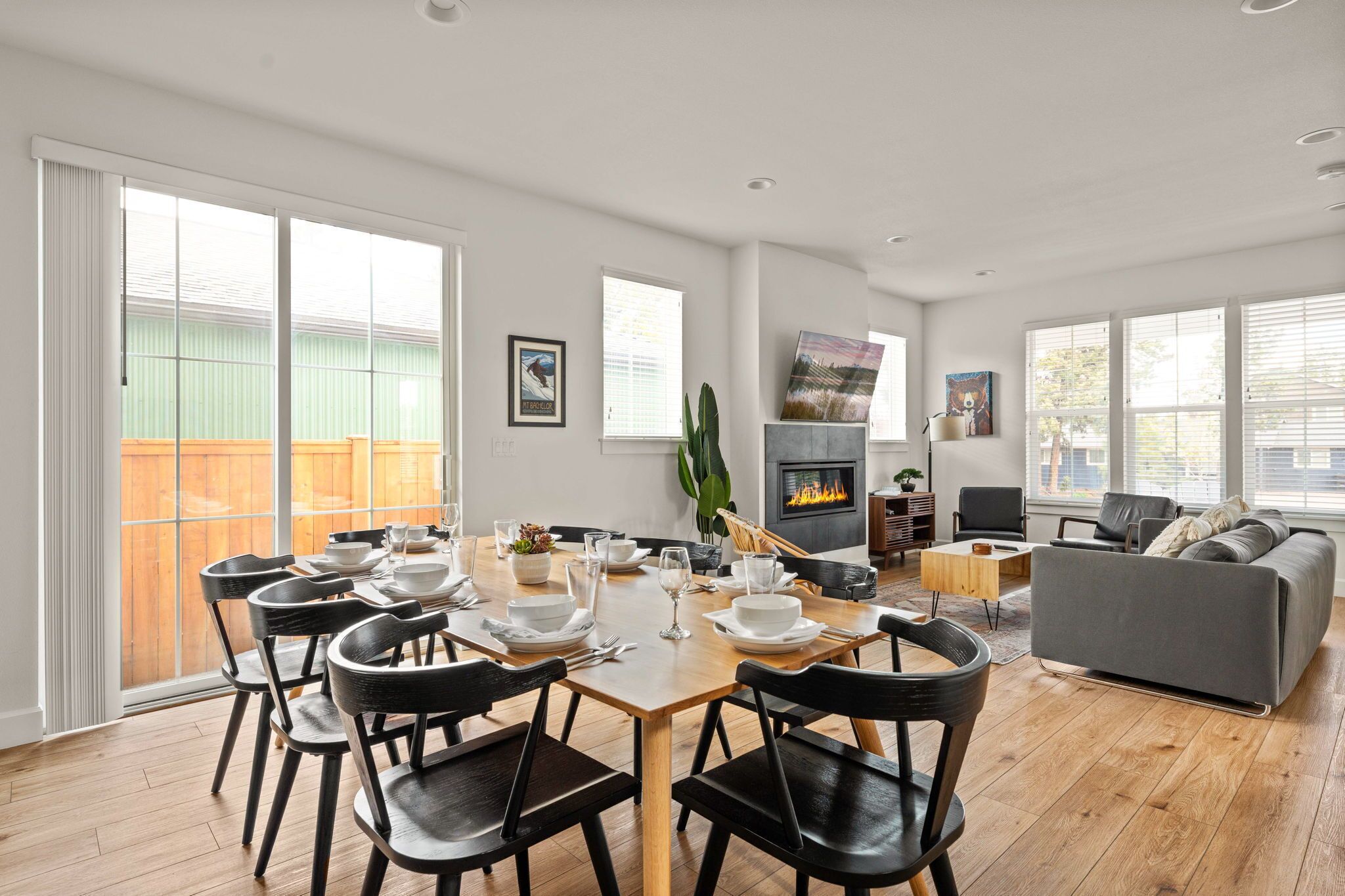 Een moderne woonkamer met een eethoek, een open haard en een groot raam.