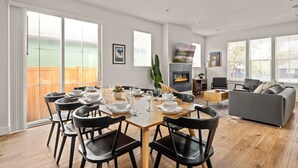 A modern living room with a dining area, a fireplace, and a large window. - Lodge with Spa, Walk to Old Mill (Bend)
