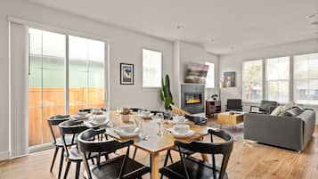 Een moderne woonkamer met een eethoek, een open haard en een groot raam.