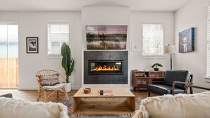 A modern living room with a fireplace, a large painting, and a cozy seating area. - Lodge with Spa, Walk to Old Mill (Bend)