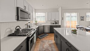 A modern kitchen with a central island, built-in appliances, and a herringbone tile backsplash. - Lodge with Spa, Walk to Old Mill (Bend)