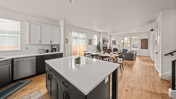 A modern kitchen with a central island, dining area with chairs, and a living room with a sofa. - Lodge with Spa, Walk to Old Mill (Bend)