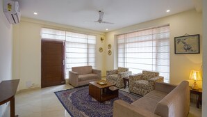 A living room with a sofa, armchairs, a coffee table, and a patterned rug. - Alayam 3 BHK by Dumnu Homes (Krishangarh)