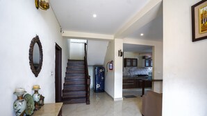A spacious living area with a staircase, a kitchen in the background, and a dining table with decorative items. - Alayam 3 BHK by Dumnu Homes (Krishangarh)