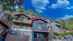 A multi-story building with balconies, stone walls, and a red roof. - Alayam 3 BHK by Dumnu Homes (Krishangarh)