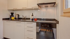 A modern kitchen with white cabinets, a built-in dishwasher, and a black oven. - Apartment Adele by Interhome (Fiesch)