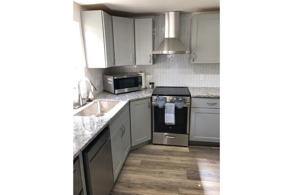 Enjoy cooking in this kitchen with stainless steel appliances, a herringbone-patterned backsplash, and ample workspace on the granite countertop.
