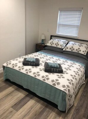 Cozy retreat with a floral-patterned bedspread and a nightstand featuring a lamp and small table.