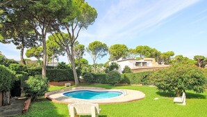 A backyard with a swimming pool, surrounded by lush greenery and trees.