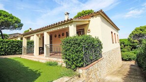 A two-story house with a tiled roof, a balcony, and a stone wall.