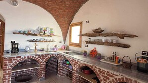 A kitchen with brick walls, a window, shelves with kitchenware, and a coffee machine. - Tala boutique accommodation 15 (Hurghada)