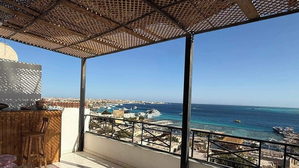 A balcony with a view of the sea, a wooden table, and a chair. - Tala boutique accommodation 15 (Hurghada)