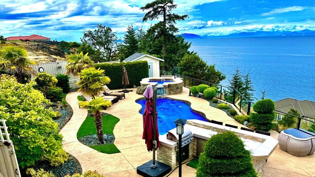 Un jardin avec une piscine, un jacuzzi et une vue sur l’océan.