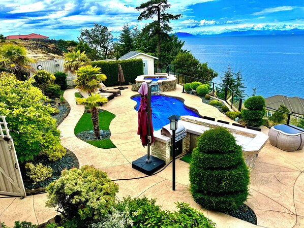 A backyard with a swimming pool, a hot tub, and a view of the ocean. - Oceanfront Gated Villa with pool & Hot tub in Nanaimo (Nanaimo)