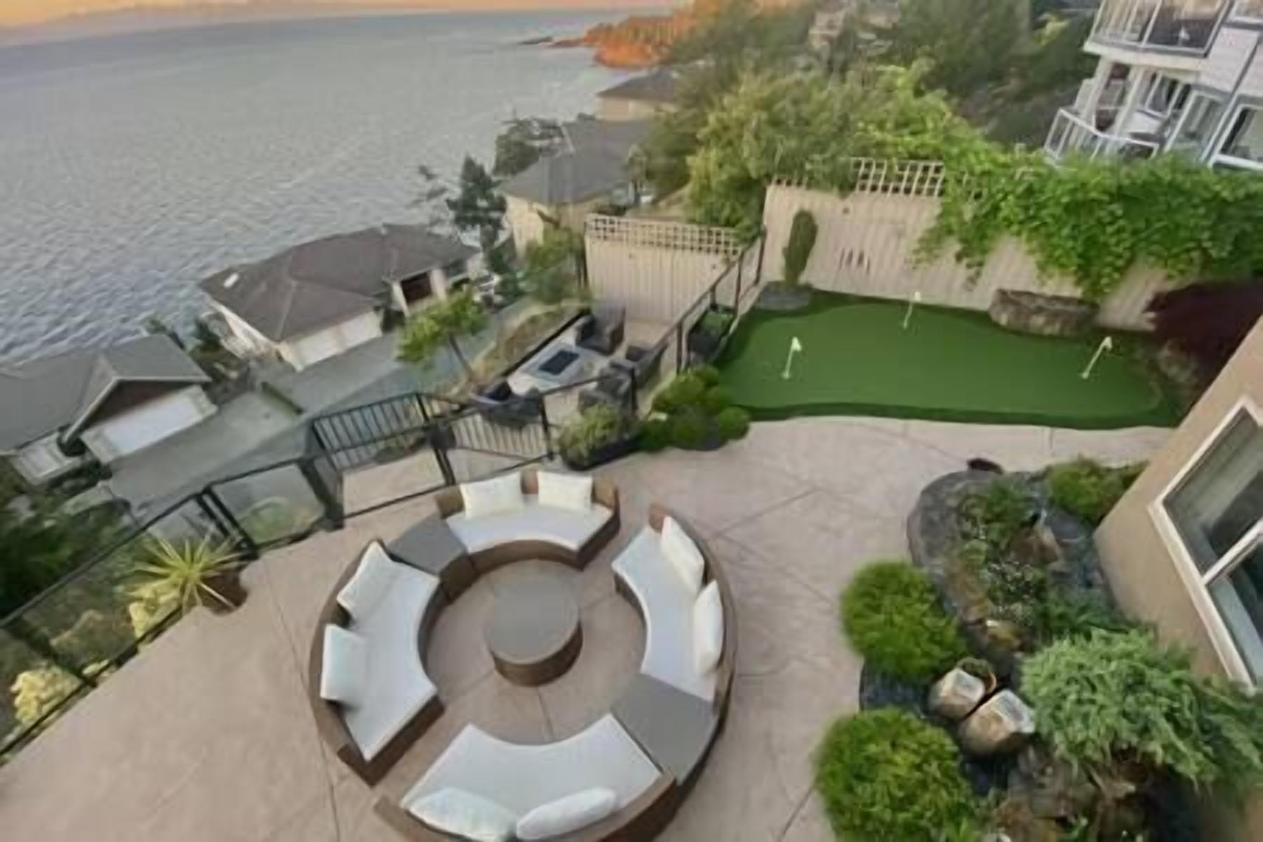 A rooftop patio with a circular seating area, a small putting green, and a view of the sea.