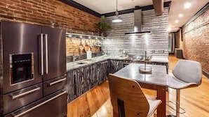 Una cocina con pared de ladrillo, electrodomésticos de acero inoxidable y una mesa de comedor de madera.