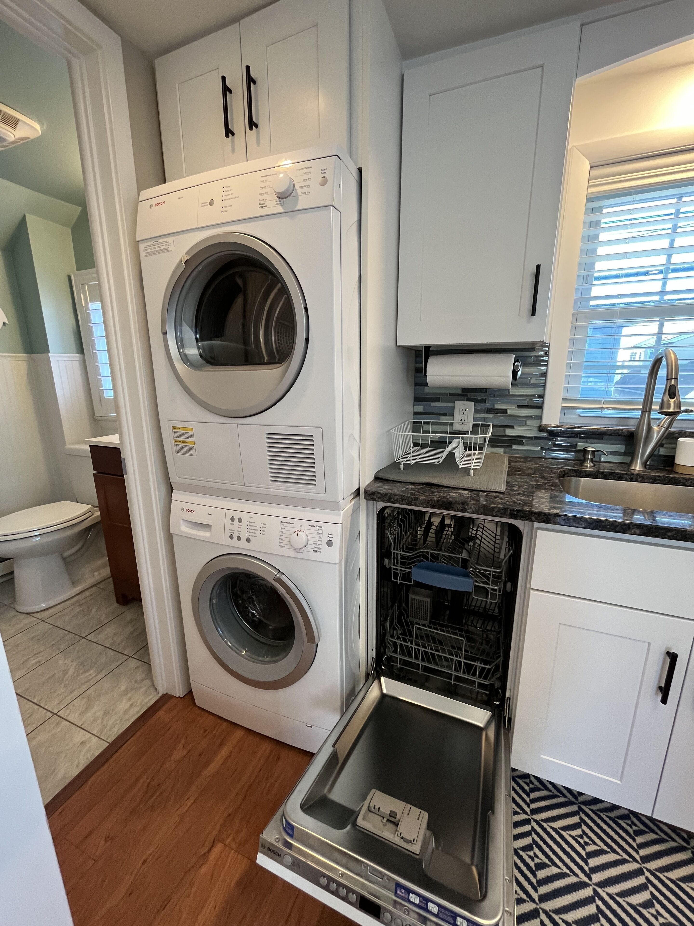 A compact kitchen with a Bosch washing machine, a dishwasher, and a sink.