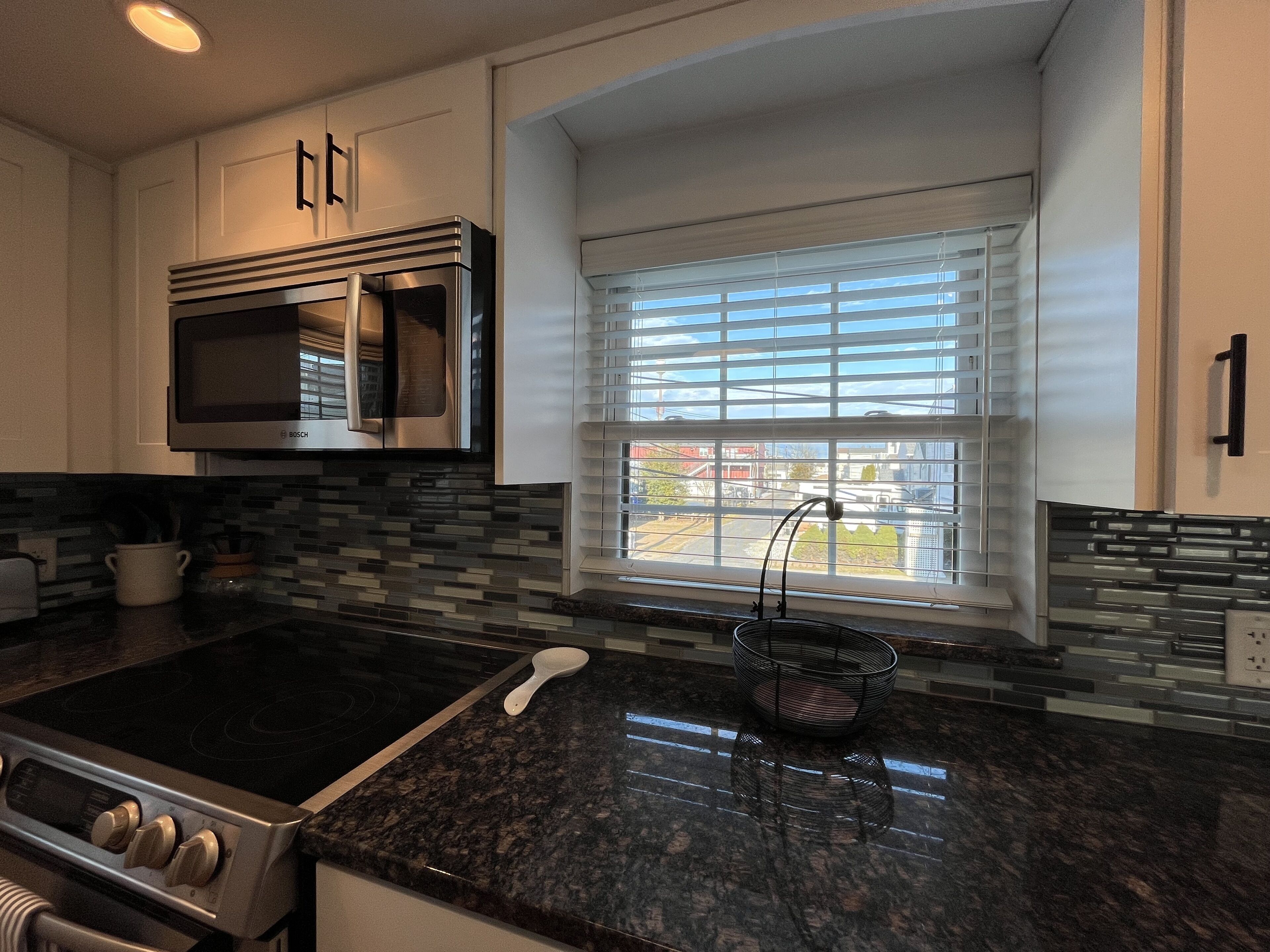 A modern kitchen with a built-in microwave, stove, and granite countertop.