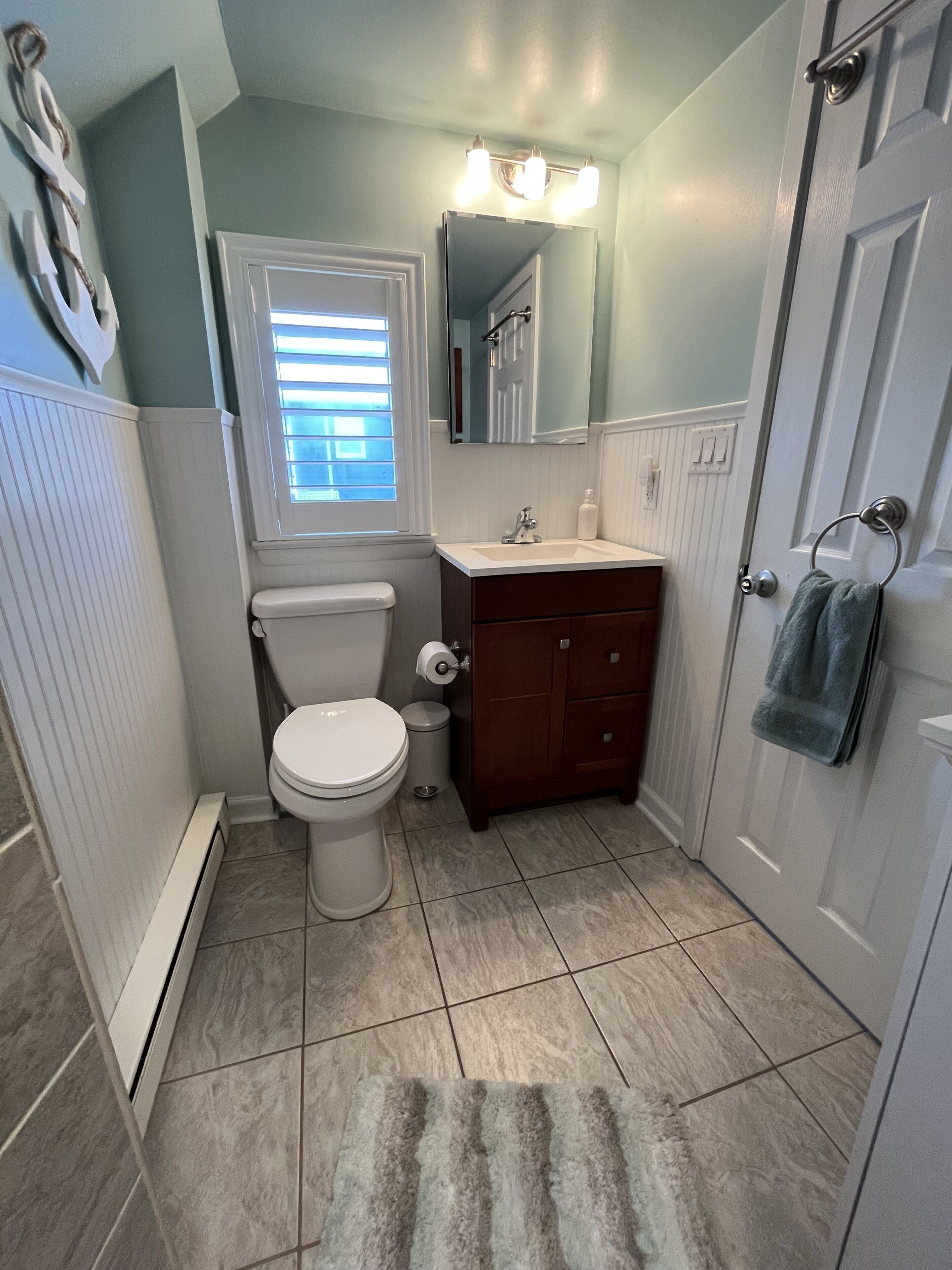 A bathroom with a toilet, sink, mirror, and towel rack.