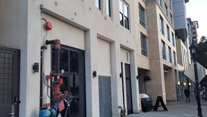 Un edificio moderno con fachada color beige, varias ventanas y un hidrante en la acera.