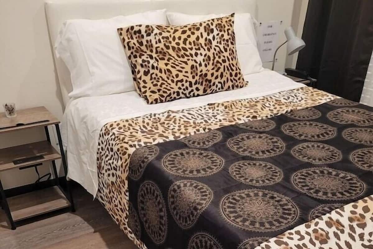 Une chambre à coucher avec un lit, une table de chevet, une lampe et une couvre-lit à motifs.