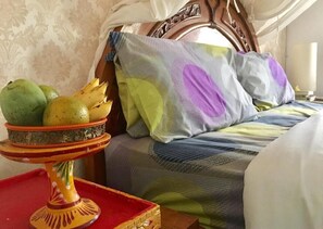 Restful retreat with a traditional bed and canopy, accompanied by a decorative fruit stand.