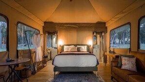 Ein gemütliches Schlafzimmer mit einem großen Bett, Holzboden, einem kleinen Tisch und einer Couch.