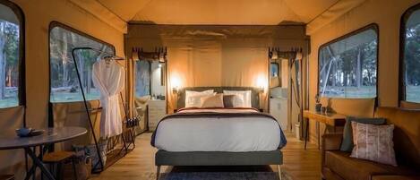A cozy bedroom with a large bed, a wooden floor, a small table, and a couch.