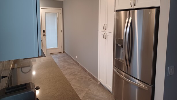 A modern kitchen with white cabinets, a stainless steel refrigerator, and a toaster.