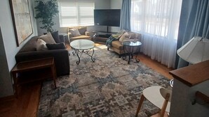 A living room with a sofa, a coffee table, a TV, and a large plant.