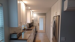 A modern kitchen with white cabinets, stainless steel appliances, and a built-in oven.