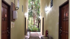 A hallway with two doors on each side, a bench, and a fire extinguisher. - Badul Homestay (Kuching)