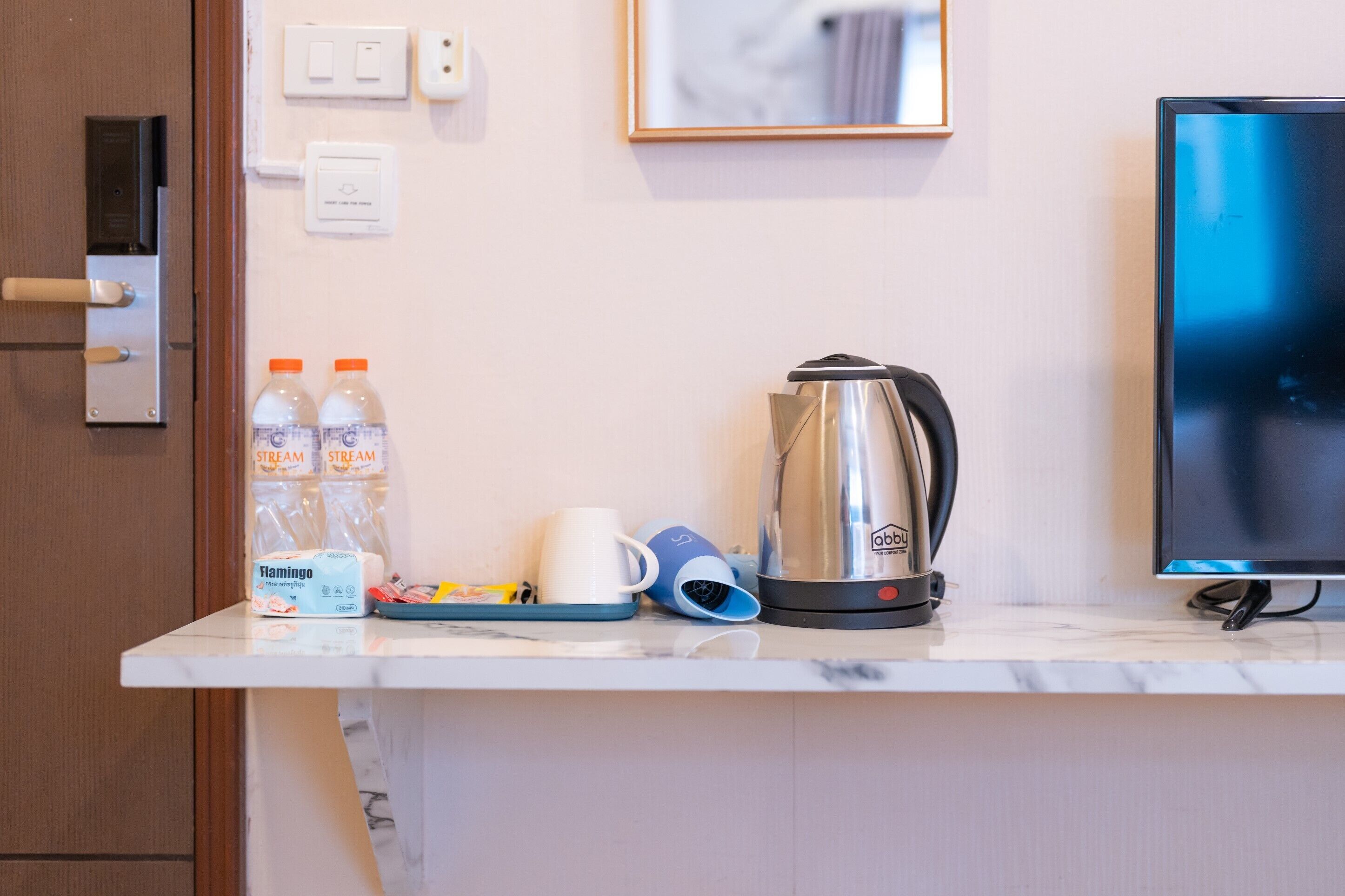 A kitchen counter with a coffee maker, bottled water, a coffee cup, and a tray.
