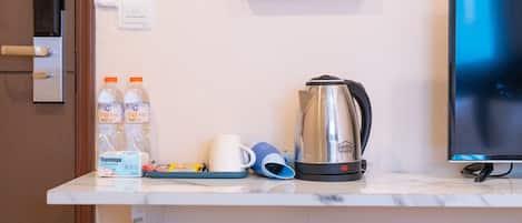 A kitchen counter with a coffee maker, bottled water, a coffee cup, and a tray.