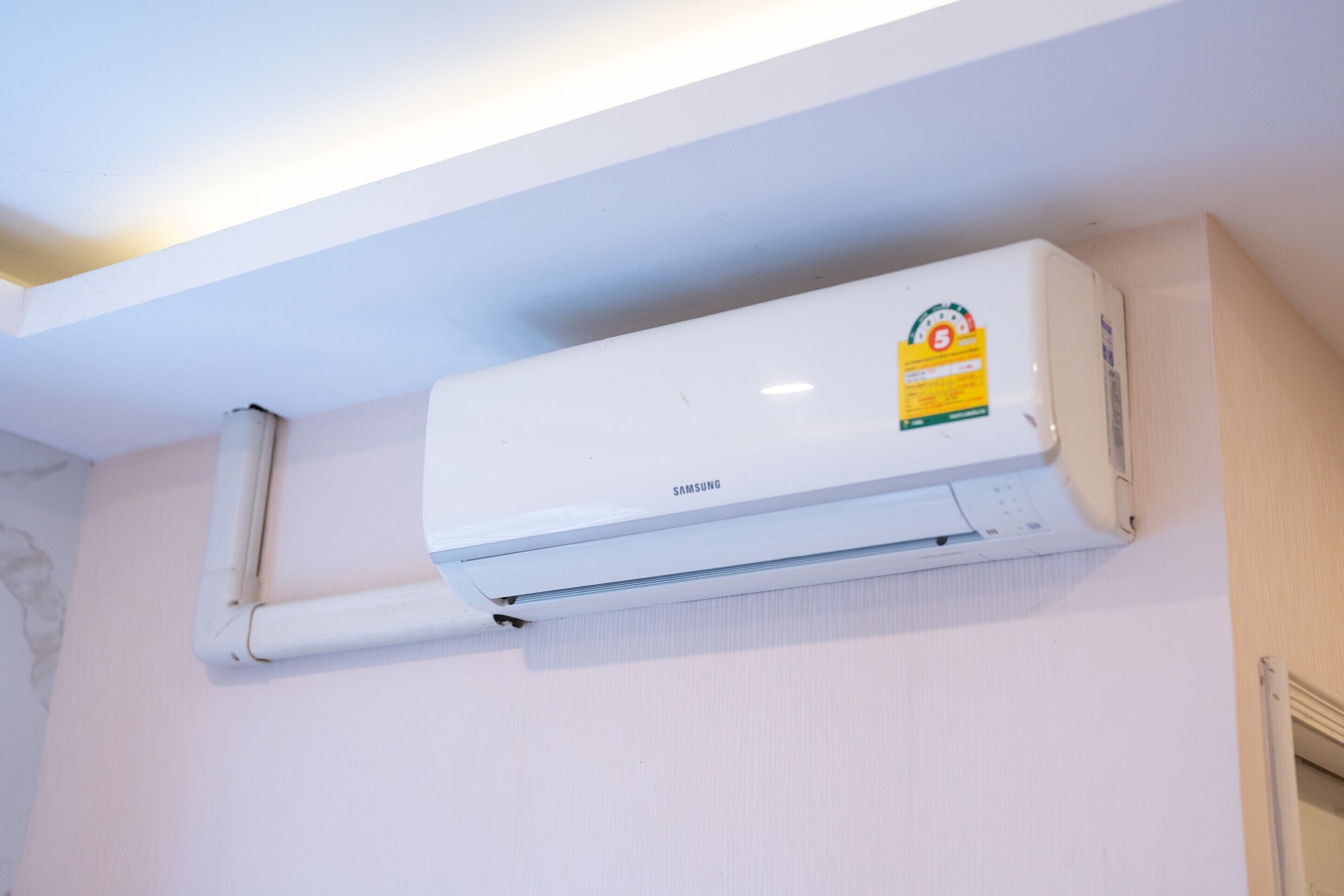 A white wall-mounted air conditioning unit with a Samsung logo and a sticker.