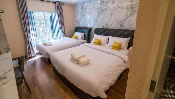 A hotel room with two beds, marble walls, and a view of the outdoors. - Amber Inn (Bangkok)