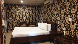 Ein Schlafzimmer mit einem großen Bett, einem Nachttisch, einer hölzernen Bank und einer Wand-Klimaanlage.