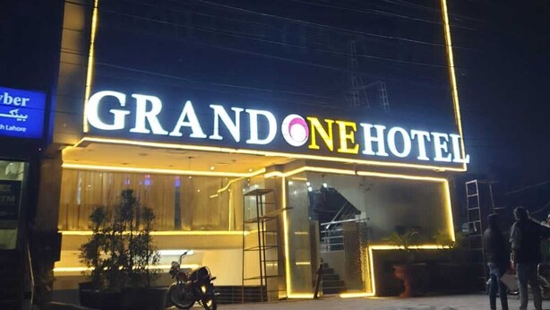Ein Hotel namens GRANDONEHOTEL mit einer gut sichtbaren, beleuchteten Signatur.