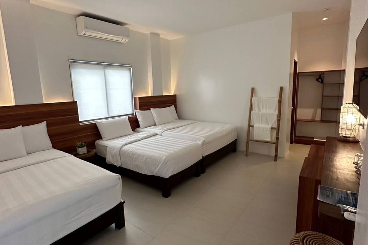 Habitación de hotel con dos camas, un escritorio, una silla y un taburete pequeño.