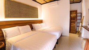 Habitación de hotel con dos camas, cabecera de madera, un tapiz grande tejido y una escalera apoyada en la pared.