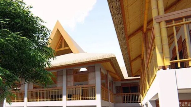 Un edificio de varios pisos con un estilo arquitectónico tradicional, que presenta balcones de madera y un patio central con zonas de estar.