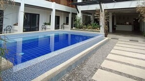 Un edificio de dos plantas con una piscina al frente.