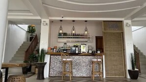 Una cocina moderna con barra, que cuenta con un salpicadero de piedra, lámparas colgantes y una variedad de electrodomésticos.