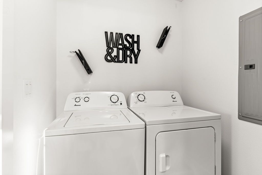 A laundry room with two white washing machines and a wall-mounted sign that reads 'WASH & DRY.'